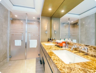Renovated bathroom with glass shower enclosure and marble countertop