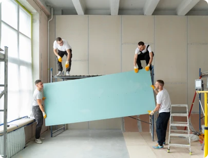 Workers installing drywall panel on a commercial renovation site