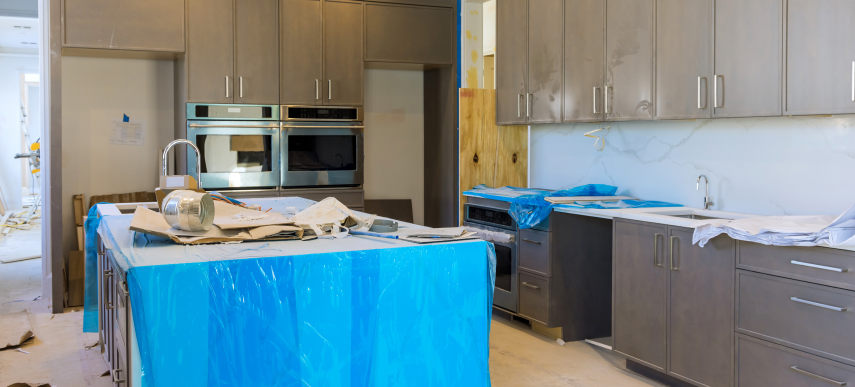 Modern kitchen renovation Toronto project featuring gray custom cabinetry, stainless steel double ovens, and protected island counter.