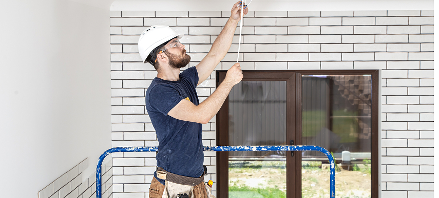 Licensed home renovation contractor working on overhead electrical and utility wiring during a tankless water heater installation